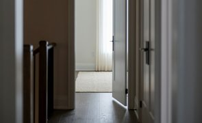 Corredor de casa com portas de madeira e maçanetas escuras, ilustrando onde entra cada linha de fechadura Haga Corredor de casa com portas de madeira e maçanetas escuras, ilustrando onde entra cada linha de fechadura Haga