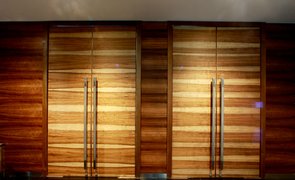 Duas portas de madeira em hall de entrada com puxadores de porta longos e verticais em perfil tubular Duas portas de madeira em hall de entrada com puxadores de porta longos e verticais em perfil tubular